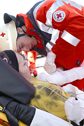 Foto: Ein DRK-Helfer vorsorgt eine junge Frau auf einer Trage medizinisch.